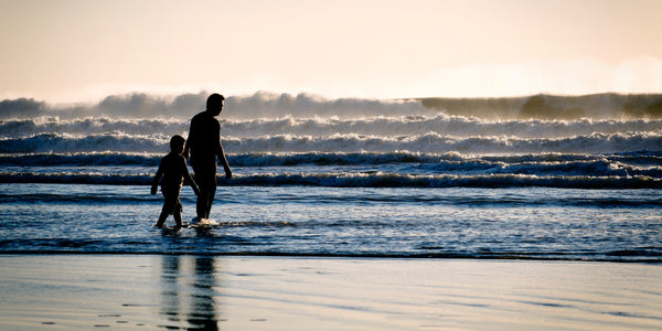 Father and son walking on a wavey sunny beach shore genetics anxiety